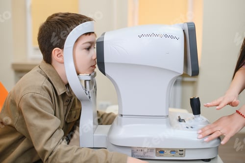 Preview: Boy undergoing eyesight examination with autorefractor in ophthalmology clinic