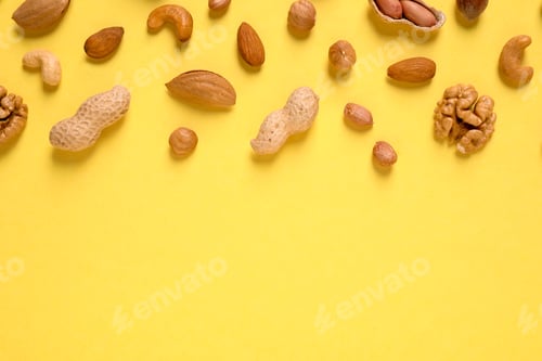 Preview: Different delicious nuts on yellow background, flat lay. Space for text