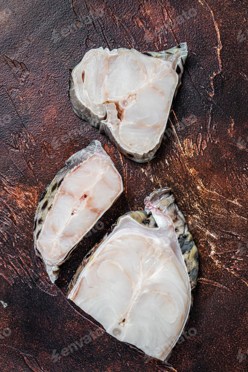 Preview: Raw atlantic wolffish fish Steak. Dark background. Top view