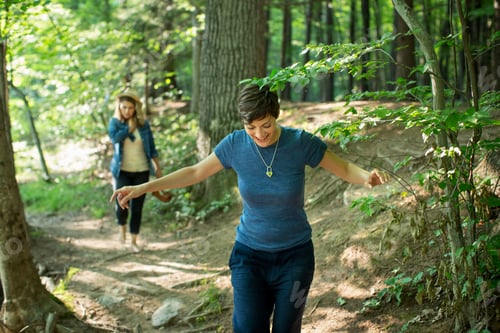 Preview: Two women walking down a woodland path.