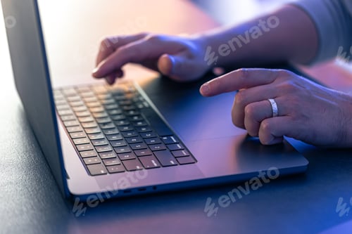 Preview: A man uses a laptop at night, close-up of his hands.