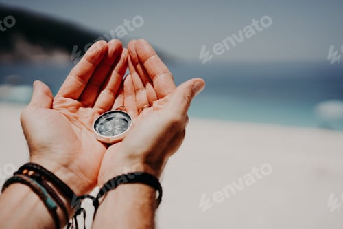 Preview: Man's hand holding compass against the backdrop of beach and sea. The concept of travel, summer