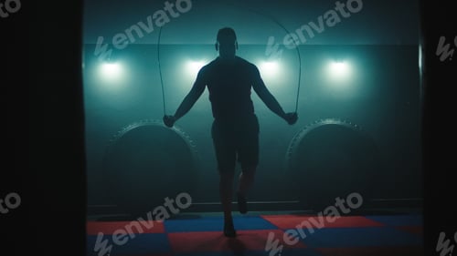 Preview: Fighter does some jump rope exercises in dark room under light