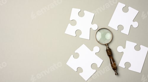 Preview: White puzzles around a magnifying glass on a gray background.
