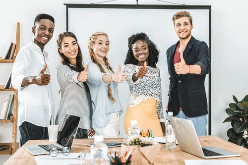 Preview: portrait of multiethnic smiling business people showing thumbs up in office