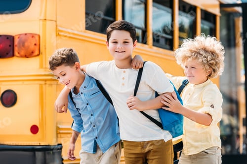 Preview: adorable little schoolboys having fun together in front of school bus