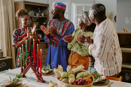 Preview: Group of Black Adults Celebrating Kwanzaa Around Table with Kinara Candles