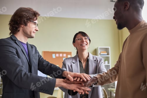 Preview: Business team of three people joining hands in unity at office