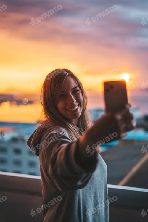 Preview: Young woman taking a selfie with the ocean on the background