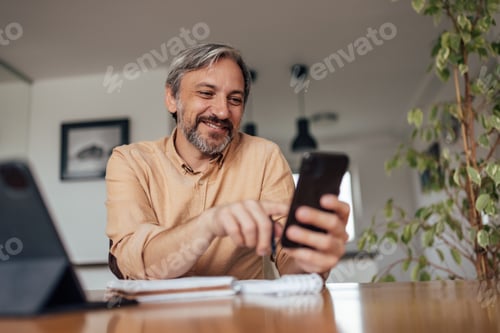 Preview: Man Smiling While Using Smart Phone at Home