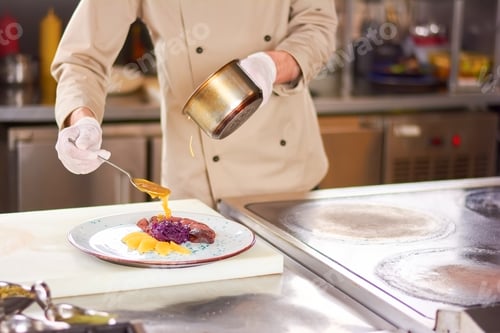 Preview: Chef pouring orange sauce on meat