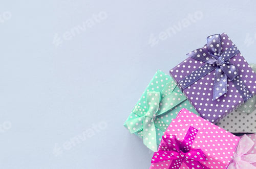 Preview: Pile of a small colored gift boxes with ribbons lies on a violet background