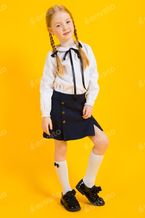 Preview: Girl with red pigtails on a yellow background. A beautiful girl is standing with her leg bent at the