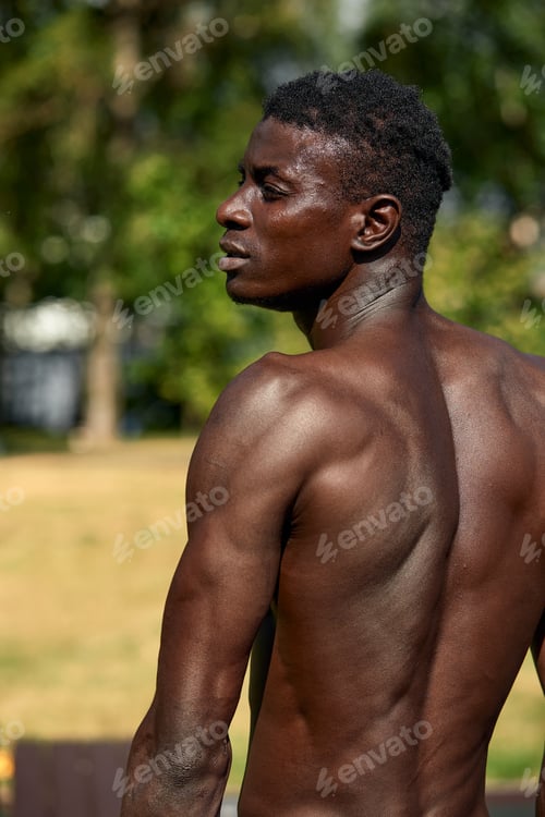 Preview: Handsome afro American runner sitting on the street while taking break after training. Black male