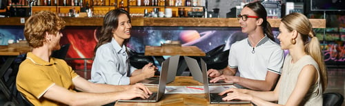 Preview: young team working using their laptops with blurred bar on background, coworking concept, banner