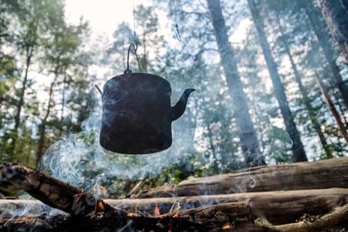 Preview: Black bowlers over a fire in the forest. Summer camp tourists.