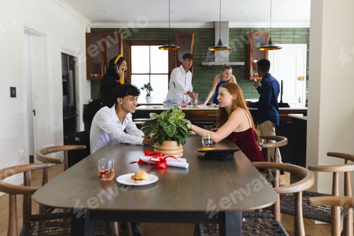 Preview: Teenagers celebrating at home, enjoying food and conversation around dining table