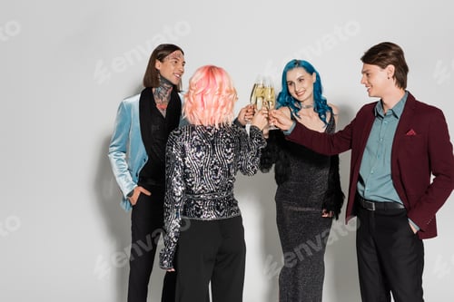 Preview: cheerful and elegant nonbinary people toasting with champagne during new year party on grey