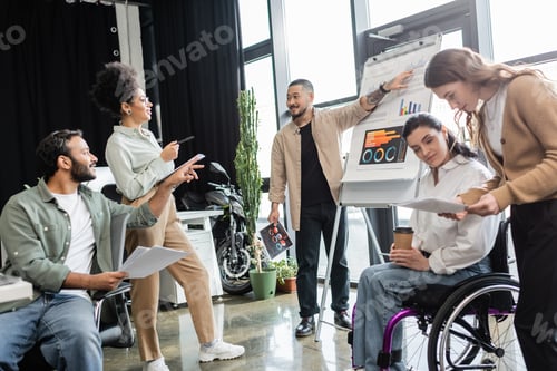 Preview: inclusion, asian man showing charts and graphs, woman in wheelchair discussing project with team