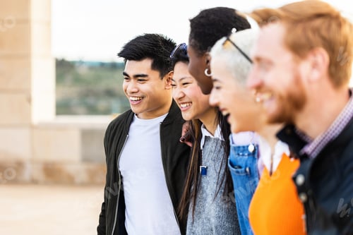 Preview: Diverse group of united young friends laughing together outdoor