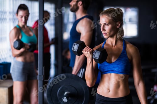 Preview: Confident woman holding dumbbells in gym