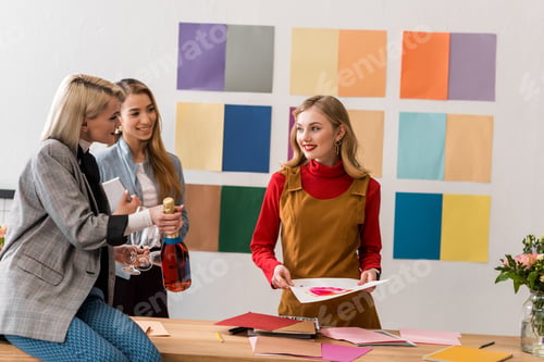 Preview: successful magazine editors celebrating with champagne in modern office with color palette