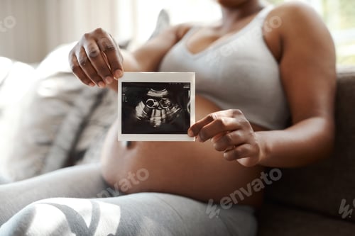 Preview: Waiting to meet my little one. Closeup shot of an unrecognisable woman holding a sonogram at home.