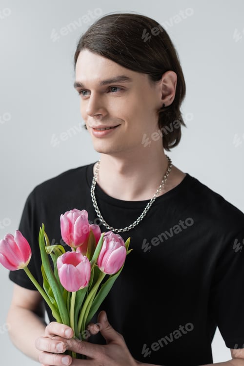 Preview: Smiling stylish man holding tulips isolated on grey
