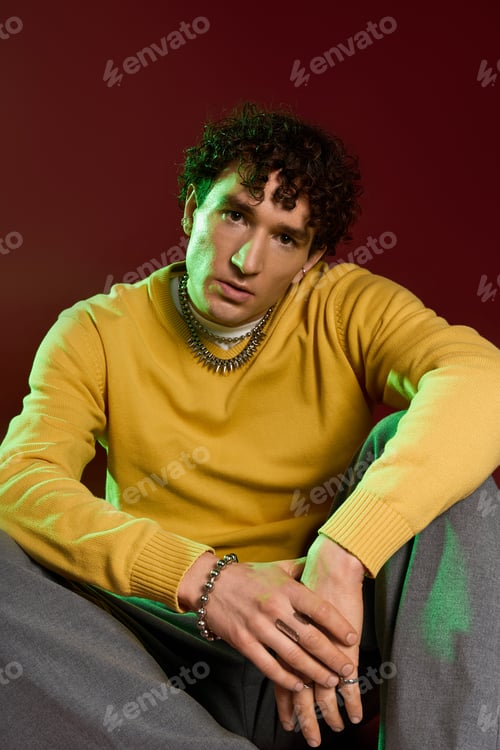 Preview: Stylish man exuding confidence in vibrant attire against a rich backdrop