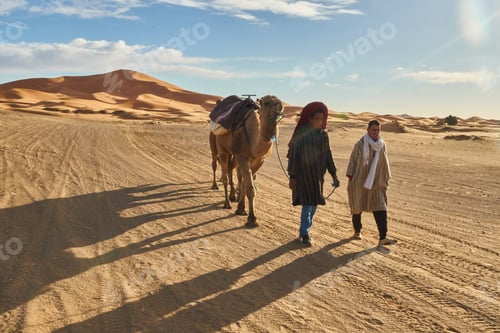 Preview: Marrakesh, Morocco - 31 December 2017: Camels and people going in desert