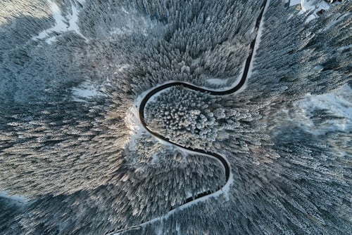 Preview: Aerial view of winter landscape with snow covered mountain hills and winding forest road in morning