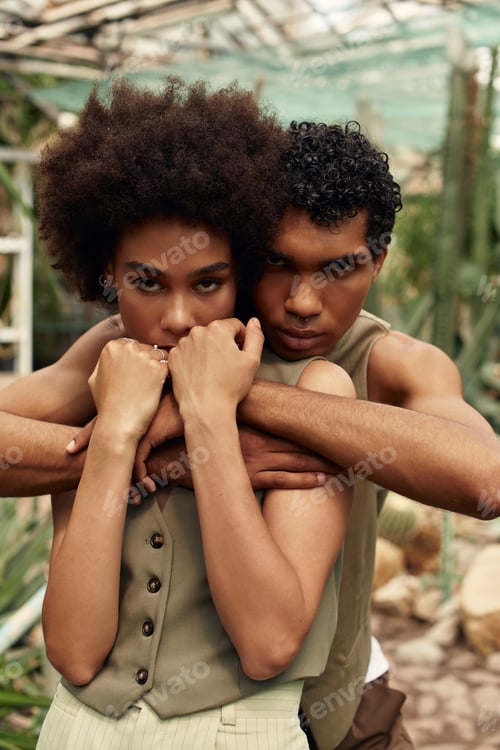 Preview: Young couple embraces in lush greenhouse filled with vibrant plants and romance