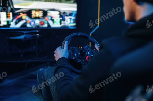 Preview: Using steering wheel. Young guy is playing racing game by using driving simulator