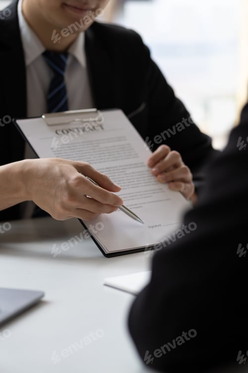 Preview: Real estate agent holding pen pointing contract document for client to sign home purchase agreement.