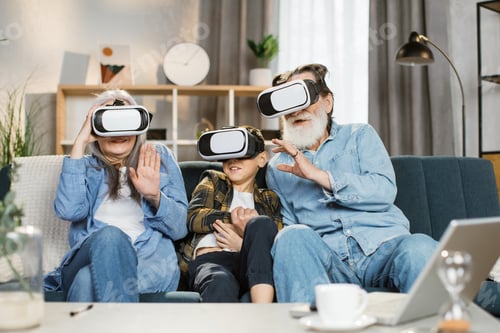Preview: Caucasian grandmother grandson and grandfather wearing vr headset sitting on couch at home