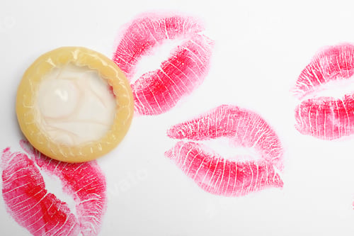 Preview: Condom and lipstick kiss marks on white background, top view. Safe sex