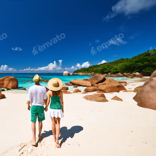 Preview: Couple In Green Walking On A Tropical Beach At Seychelles