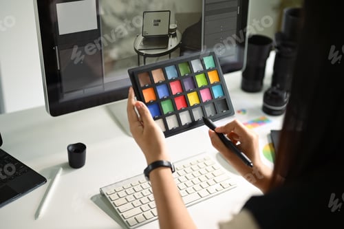 Preview: Creative woman holding a color palette in front of a computer monitor