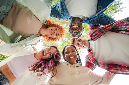 Preview: Low angle view of a group of multiracial happy young teenagers hugging each others in a circle
