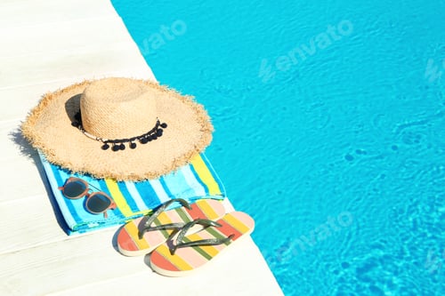 Preview: Beach accessories on wooden deck near swimming pool. Space for text