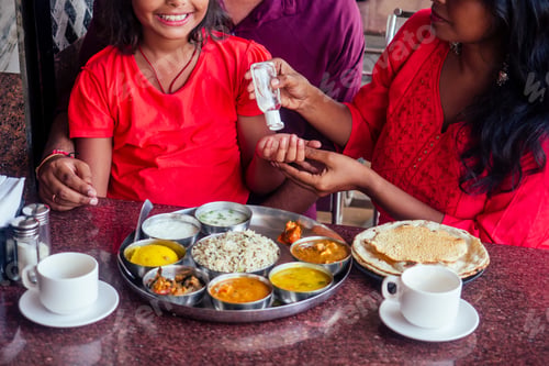 Preview: Father ,mother and little girl using wash hand sanitizer gel before eating in india cafe