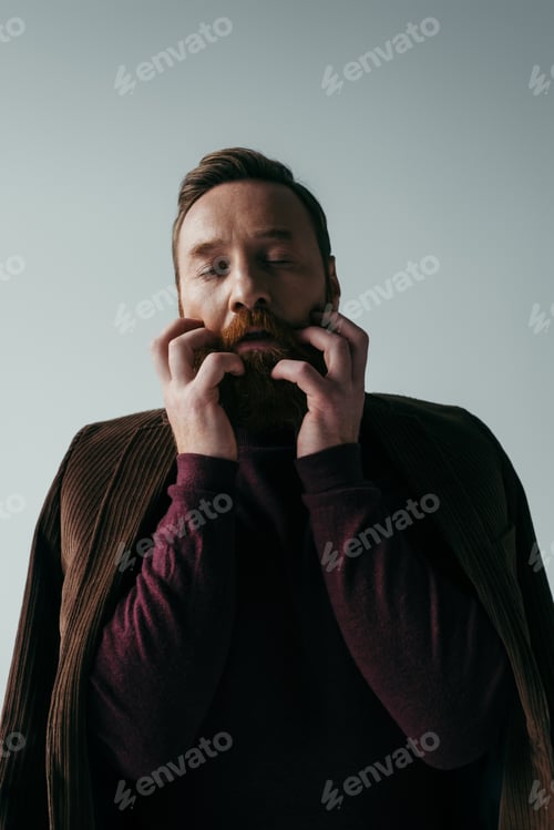 Preview: man in turtleneck and blazer scratching beard isolated on grey