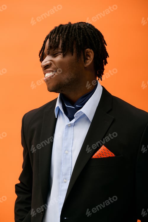 Preview: Stylish young man smiles confidently against a vibrant orange backdrop