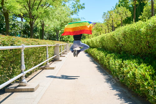 Preview: A man is jumping in the air with a rainbow flag.