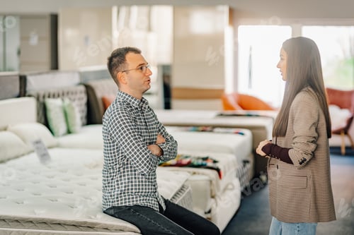 Preview: Couple discussing mattress options in furniture store
