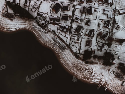 Preview: Aerial view of a cityscape with snow-covered roofs of houses and a tranquil body of water