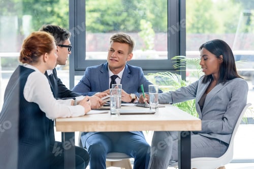 Preview: Behind the glass view of executives discussing project in modern office