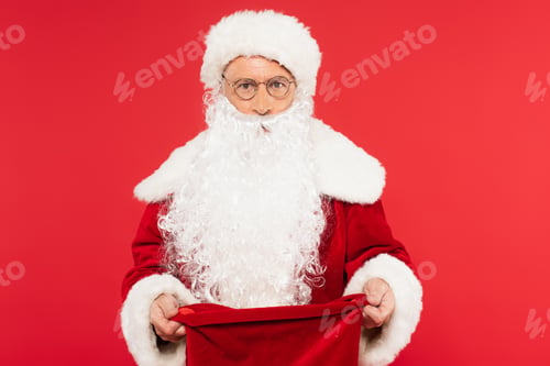 Preview: Santa claus with open sack looking at camera isolated on red