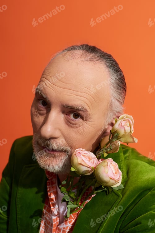 Preview: portrait of positive grey haired man with groomed beard and expressive gaze posing with roses