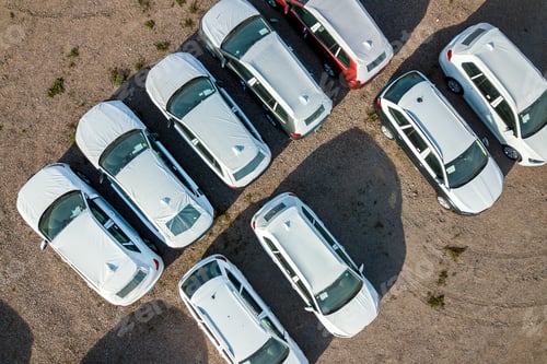 Preview: Many brand new cars covered in protective foil on sale parked outside on dealer parking lot